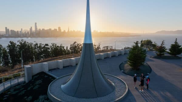 Visitors gathered near a modern overlook sculpture on Treasure Island with sweeping sunset views of the San Francisco skyline and bay.