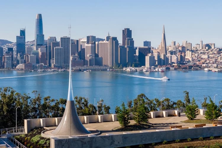 Elevated view from Treasure Island featuring a sculptural overlook, San Francisco skyline, and sparkling Bay waters on a clear day.