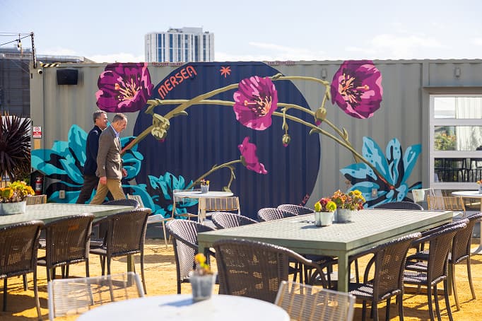 Outdoor dining patio on Treasure Island featuring colorful floral mural art and casual waterfront seating.