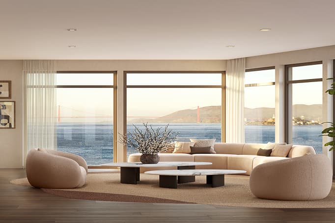 A stylish, sunlit living room with soft neutral furnishings and floor-to-ceiling windows showcasing sweeping waterfront views and the Golden Gate Bridge in the distance.
