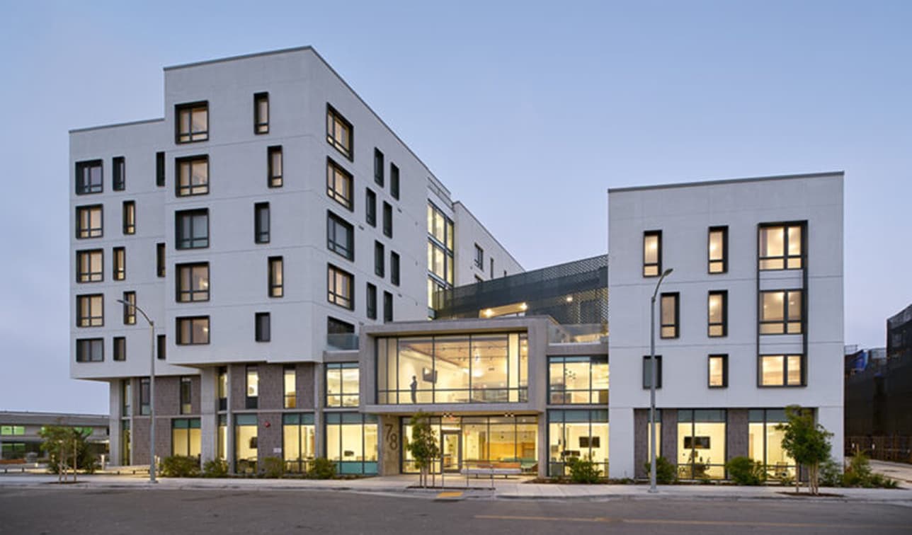 exterior of Star View Court affordable housing development on Treasure Island, featuring modern mid-rise apartment buildings, landscaped pedestrian pathways, and street-level community spaces in San Francisco.