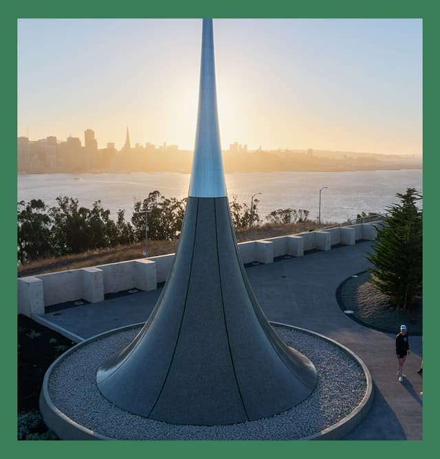 The Point of Infinity sculpture at Panorama Park with the San Francisco skyline illuminated by the rising sun across the bay.
