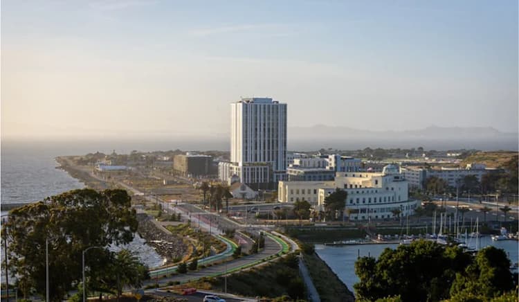 Aerial view of Treasure Island with new development rising along the waterfront, including residential towers, roads, and bay views.